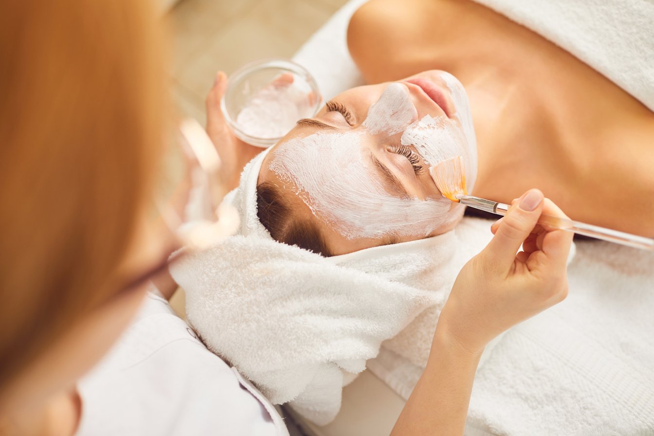 Young Girl Receiving White Facial Mask in Spa Beauty Salon.